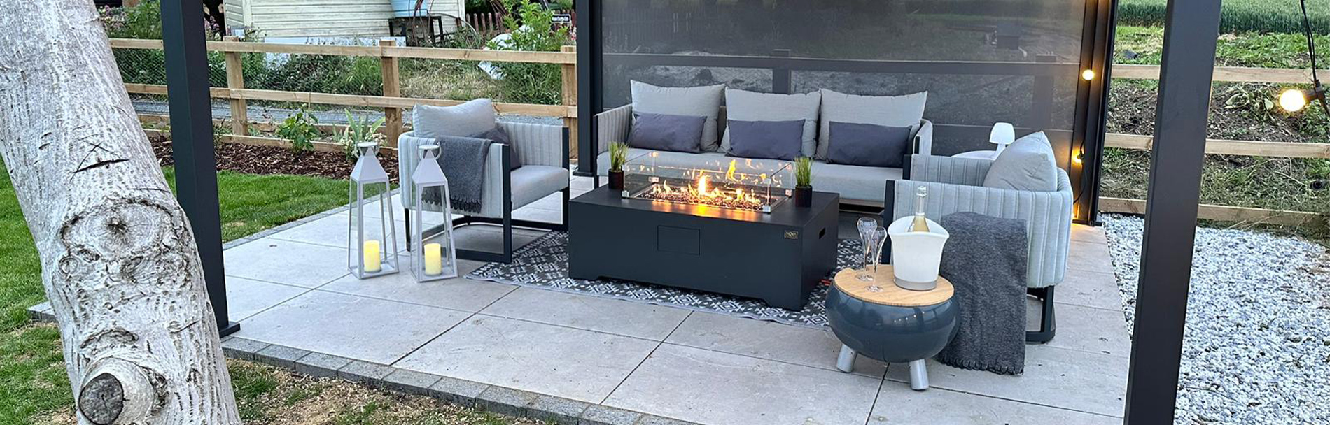 Oakley all-weather fabric garden furniture on a patio underneath a pergola with a fire pit table.