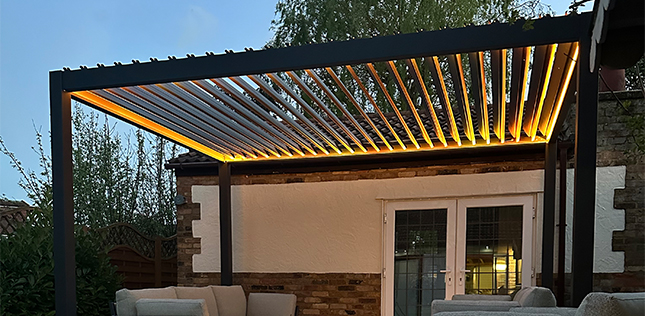 Grey aluminium pergola with LED lights over a fabric sofa set