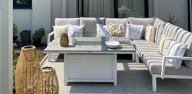 white metal corner sofa set with gas fire pit table under a metal white pergola